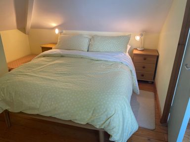 A bedroom with a bed with light bedding flanked by two wooden nightstands with lamps at Rocklea Seaside Cottage in Newcastle County Down