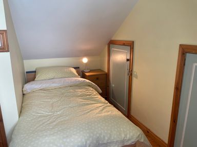 A small bedroom with a single bed nightstand and lamp under a sloped ceiling at Rocklea Seaside Cottage in Newcastle County Down