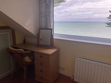 A wooden desk with a mirror and chair beside a window showing a sea view at Rocklea Seaside Cottage in Newcastle County Down
