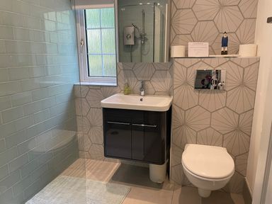 A bathroom with a sink cabinet toilet and window at Rocklea Seaside Cottage in Newcastle County Down
