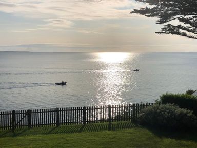 A view of the sea with two boats on the water a wooden fence and grass in the foreground at Rocklea Seaside Cottage Newcastle County Down