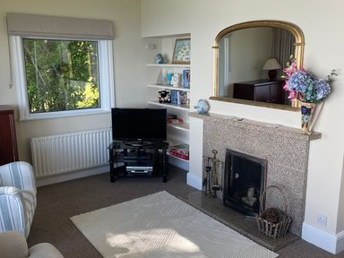 A living room with a fireplace mirror TV shelf and armchair at Rocklea Seaside Cottage in Newcastle County Down