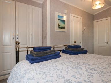 A bedroom with a bed covered in a patterned bedspread and neatly folded towels on top at Sycamore Lodge Porkellis near Helston
