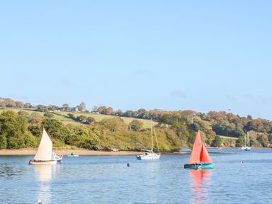 A river with sailboats and trees on the bank at Sycamore Lodge in Porkellis near Helston