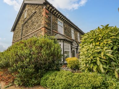 Exterior view of a stone house with large bushes in front at Hollywood in Windermere