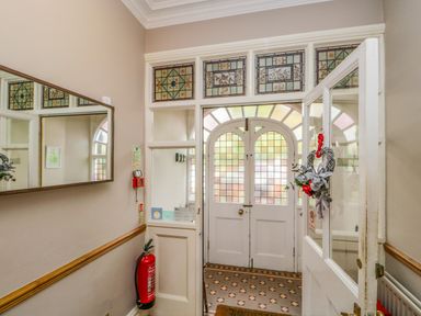 An entrance hall with a stained glass front door a fire extinguisher a wall mirror and a wreath on the door at Hollywood in Windermere