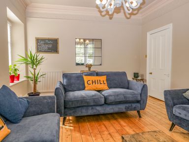 A living room with blue sofas wooden floor plants and a mirror on the wall at Hollywood in Windermere