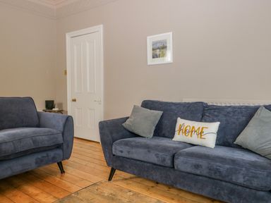 A living room with blue sofas and cushions a wooden floor and a white door at Hollywood in Windermere