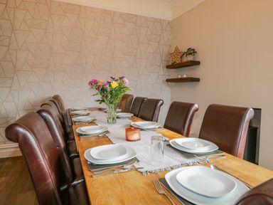 A dining room with a wooden table set with plates glasses cutlery and a flower vase in the center at Hollywood in Windermere