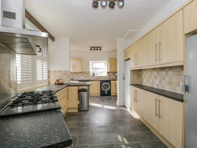 A kitchen with light wood cabinets black countertops a gas stove a washing machine and a window at Hollywood in Windermere