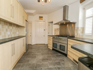 A kitchen with light wood cabinets black countertops a stainless steel stove and a tiled floor at Hollywood in Windermere