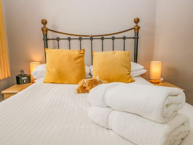 A bed with yellow pillows and folded white towels with lamps on wooden nightstands at Hollywood in Windermere
