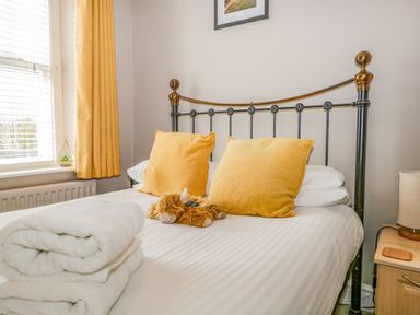 A bedroom with a metal bed frame yellow pillows a stuffed animal folded towels on the bed and a bedside table lamp at Hollywood in Windermere