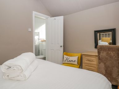 A bedroom with a bed with white towels a yellow chair with a home pillow and a wooden dresser with a mirror at Hollywood in Windermere