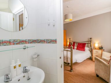 A bathroom with a sink and mirror next to a bedroom with a bed and red pillows at Hollywood in Windermere