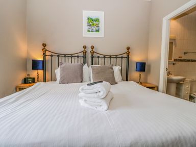 A bedroom with a double bed two bedside tables with lamps folded towels on the bed and an adjacent bathroom at Hollywood in Windermere