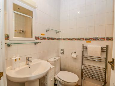 A bathroom with a sink toilet mirror towel rack and soap dispensers at Hollywood in Windermere