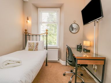 A bedroom with a single bed a desk a chair a wall-mounted tv and a window at Hollywood in Windermere