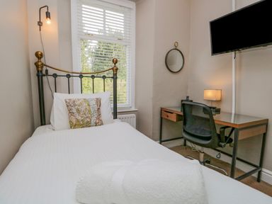 A bedroom with a single bed a desk chair and a wall-mounted TV at Hollywood in Windermere