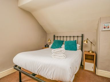 A bedroom with a bed with white linens teal pillows and folded towels and bedside tables with lamps at Hollywood in Windermere
