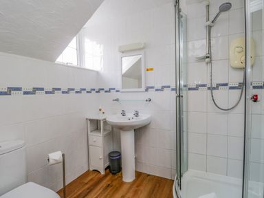 A bathroom with a shower cubicle sink toilet small storage unit and wooden floor at Hollywood in Windermere