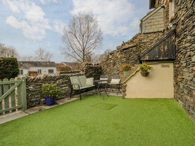 An outdoor patio area with artificial grass seating and a stone wall at Hollywood in Windermere