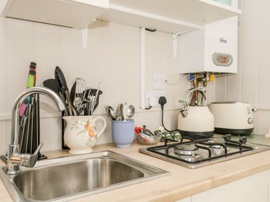 A kitchen counter with a sink utensils a kettle toaster and a gas stove at Seashore Shepherds Hut @ Moat Farm Aldingham near Ulverston