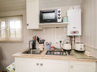 A kitchen counter with a sink stove kettle toaster and microwave at Seashore Shepherds Hut @ Moat Farm in Aldingham near Ulverston