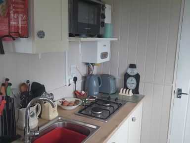 A kitchen with a gas stove and microwave at Seashore Shepherds Hut @ Moat Farm Aldingham near Ulverston