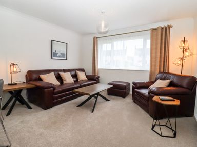 A living room with brown leather sofas a coffee table and lamps at 3 Granbrook Lane in Mickleton Gloucestershire