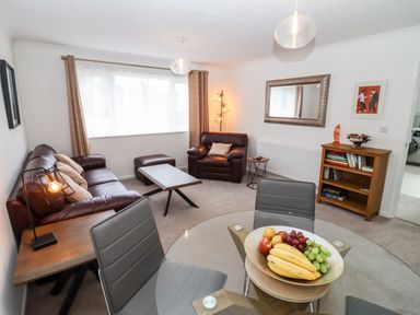 A living room with leather sofas a coffee table a glass dining table with chairs and a fruit bowl at 3 Granbrook Lane in Mickleton Gloucestershire