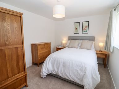 A bedroom with a double bed two bedside tables wooden dresser wardrobe and framed pictures at 3 Granbrook Lane Mickleton Gloucestershire