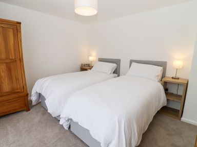 A bedroom with two single beds bedside tables with lamps and a wooden wardrobe at 3 Granbrook Lane in Mickleton Gloucestershire