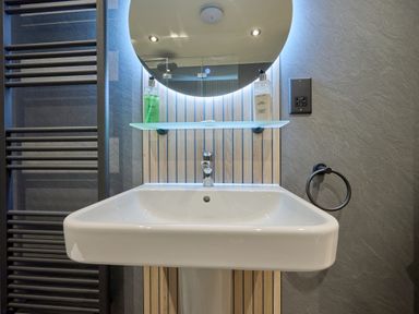 A wash basin with a mirror and shelf at Riverside Park 1 in Keswick