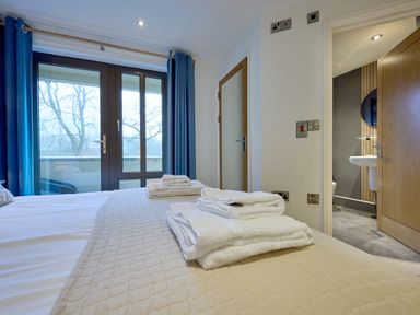A bedroom with two doors and towels on the bed at Riverside Park 1 in Keswick