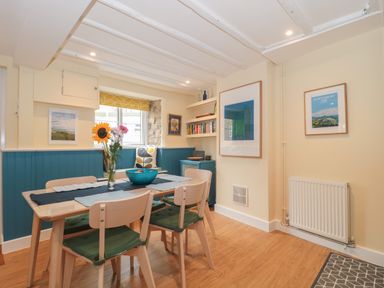 A dining area with a wooden table and four chairs with green cushions at Holly Cottage in West Coker