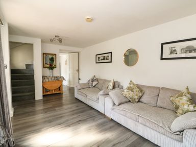 A living room with two sofas pillows a folding table mirror and framed pictures at Chalk Cottage in Feltwell