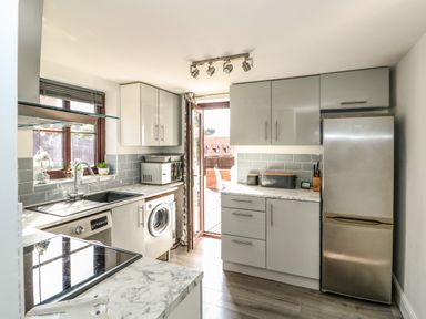 A kitchen with marble countertops a washing machine microwave refrigerator and cabinets at Chalk Cottage in Feltwell