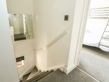 A stairway with grey carpet leading down and a bunk bed visible in a room at Chalk Cottage in Feltwell