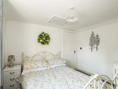 A bedroom with a metal bed frame floral bedding nightstand with lamp and wall decorations at Chalk Cottage in Feltwell