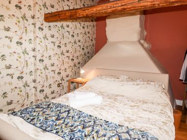 A bedroom with a bed a side table with a lamp and floral wallpaper at Eagle Farmhouse in Glenridding