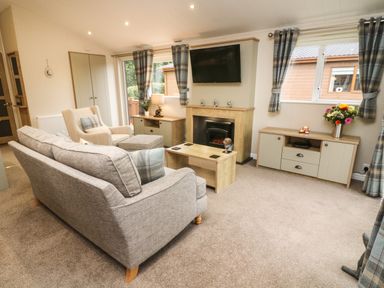 A living room with a sofa armchair coffee table fireplace and television at The Warren in Hellifield
