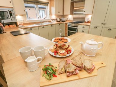 A kitchen with sandwiches salad teapot scones cookies and mugs on the counter at The Warren in Hellifield