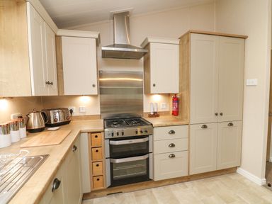 A kitchen with cabinets a stainless steel stove and oven toaster kettle and cutting board at The Warren in Hellifield