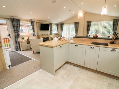 An open kitchen and living room with cabinets and a flat screen tv at The Warren in Hellifield