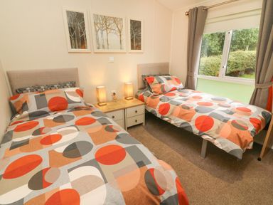 A bedroom with two single beds beside a window and a bedside table with lamps at The Warren in Hellifield