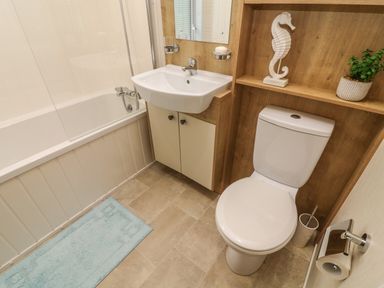 A bathroom with a bathtub sink toilet and a shelf with a seahorse decoration and a plant at The Warren in Hellifield