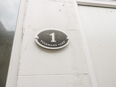 A house number plaque with the number 1 and street name Tyermans Yard on a white wall at 24 Baxtergate in Whitby