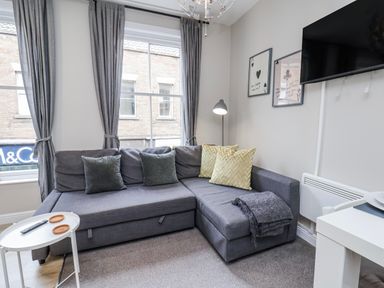 A living room with a sectional sofa and a television at 24 Baxtergate, Whitby