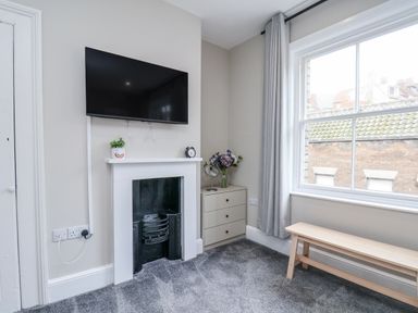 A living room with a television, fireplace and window at 24 Baxtergate in Whitby